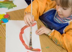 Girl with artist brush painting on paper